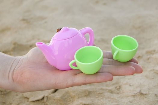 Toy cups on female hand on the beach