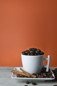 Cup of coffee and beans on an orange vintage background.