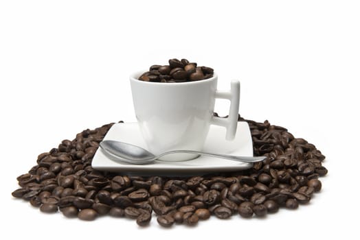 A cup and a lot of coffee beans isolated over a white background.