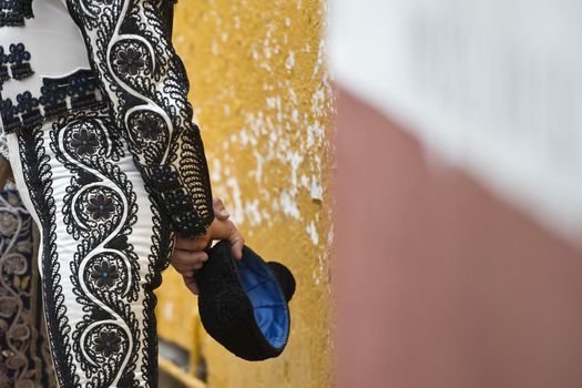 A matador holding his cap with his hands.