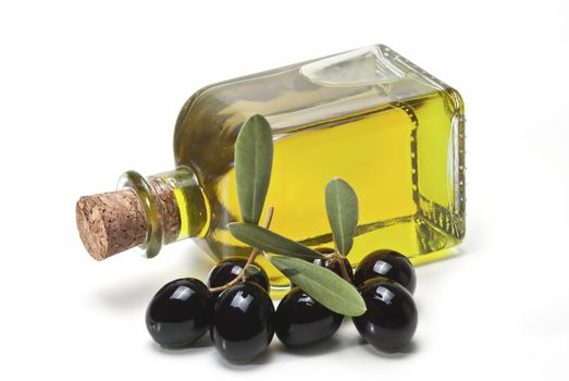 A jar with olive oil and some black olives isolated over a white background.
