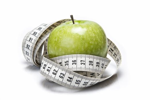 Measuring tape wrapped around a green apple as a symbol of diet.