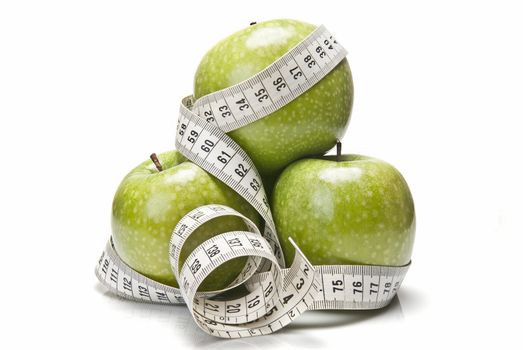 Measuring tape wrapped around a green apple as a symbol of diet.