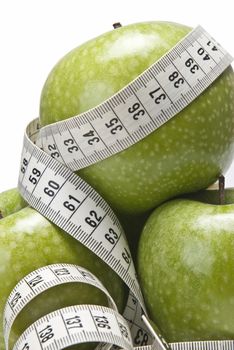 Measuring tape wrapped around a green apple as a symbol of diet.