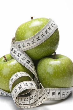 Measuring tape wrapped around a green apple as a symbol of diet.