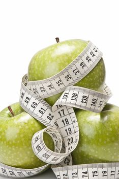 Measuring tape wrapped around a green apple as a symbol of diet.