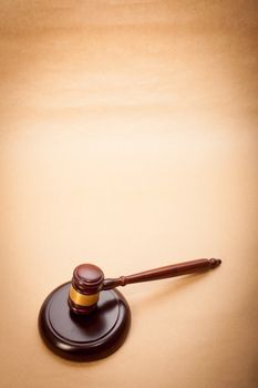 A wooden gavel and soundboard on a light brown background.
