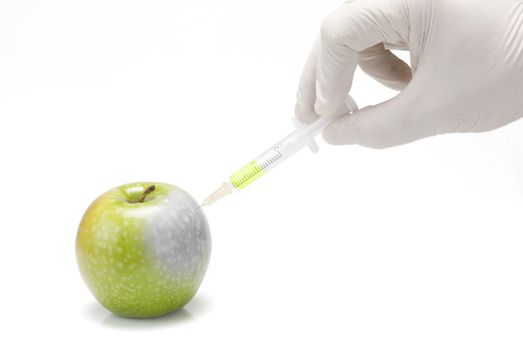 A gloved hand injecting an apple with a syringe on a white background.