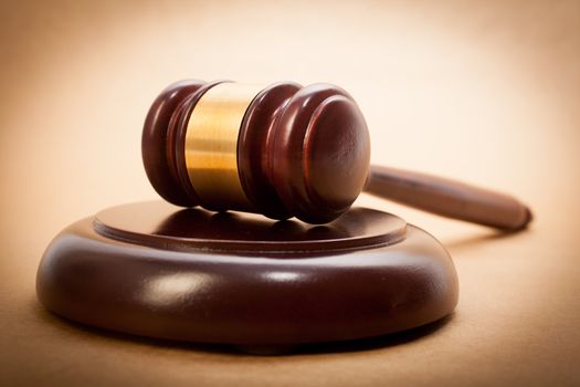 A wooden gavel and soundboard on a light brown background.