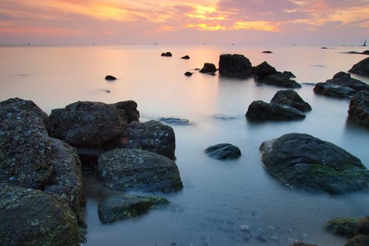 Landscape of sea with wave and rock in sunset.