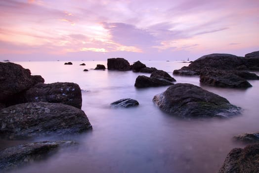 Landscape of sea with dramatic wave and rock in sunset.