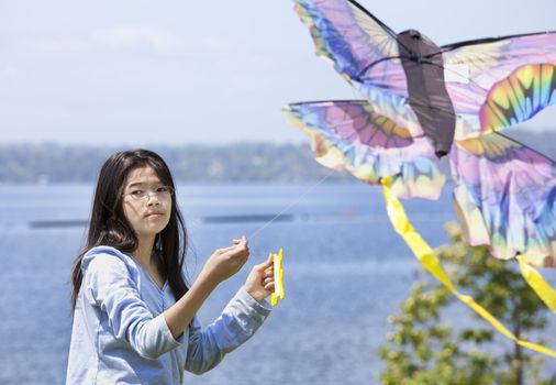 Biracial asian girl flying kite by the lake