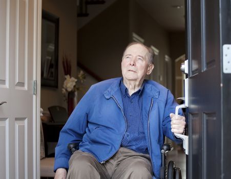 Elderly 90 yr old man in wheelchair at his front door, looking up towards sky