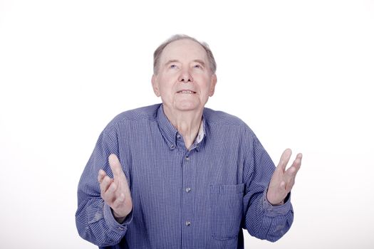 Elderly caucasian man looking up with expectant look, hands raised, as if exasperated or expectant.