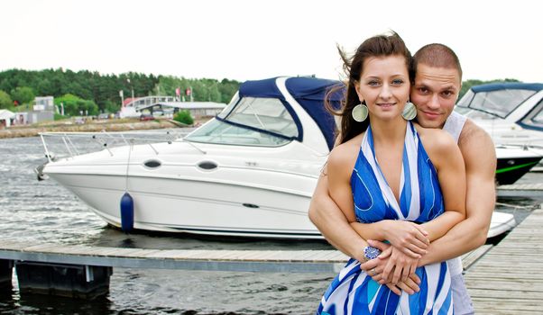 Young couple against pier with boats.