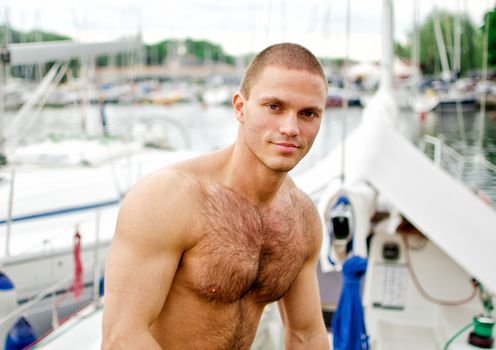 Muscular handsome sailor on his yacht.