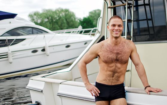 Muscular handsome sailor on his yacht.