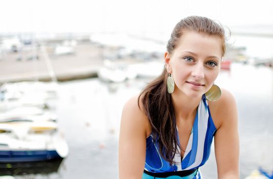 Pretty girl portrait, against of the pier with yachts.