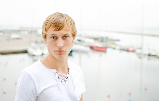 Handsome male portrait, against of the pier with yachts.