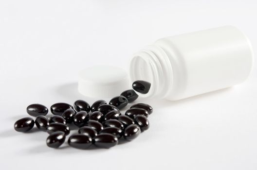 Pills spilling out of  pill bottle on white background