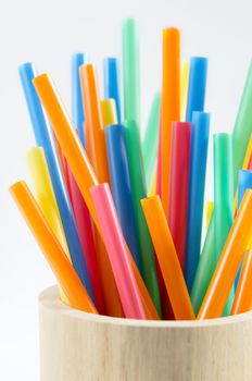 colorful drinking straws in wooden cup .