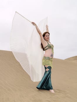 Pose of arab dance on the sand with wings