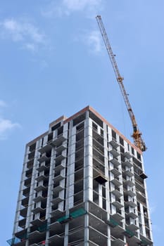 Building crane and building under construction against blue sky