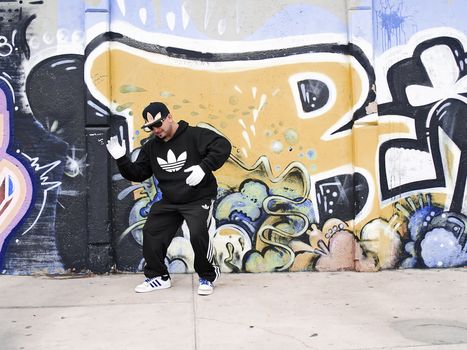 Street rapper dancing  near a graffited wall