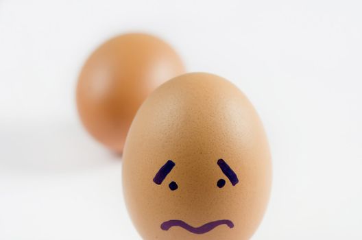 close-up brown eggs with sad face on white background