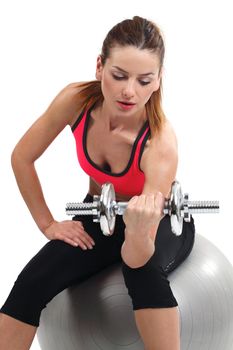 Photo of an attractive female doing dumbbell curls while sitting on an exercise ball.