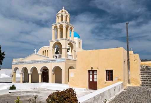 Yellow greek church with arcade porticos and belltower