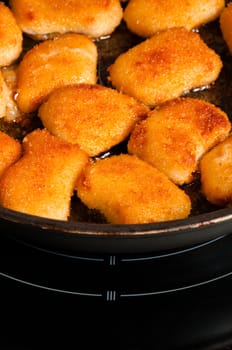 Few fried nuggets on metal pan at dark kitchen