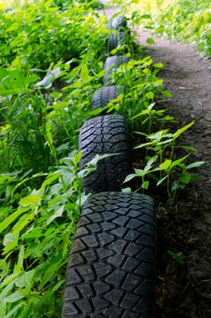 Forest path strengthen with old used car tires. Interesting decoration. Nature pollution.