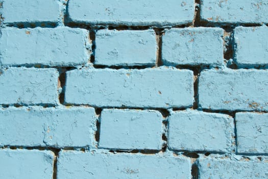 A section of a brick wall painted with a pastel blue colour.