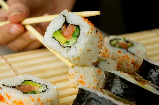 Hand holding sushi. Bamboo napkin in background