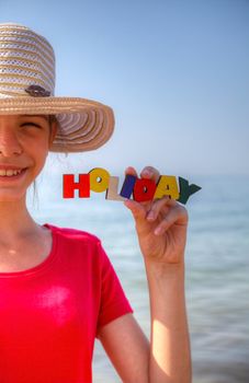 Teen girl at a beach holding word 'Holiday'