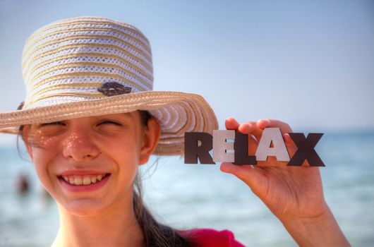 Teen girl at a beach holding word 'Relax'