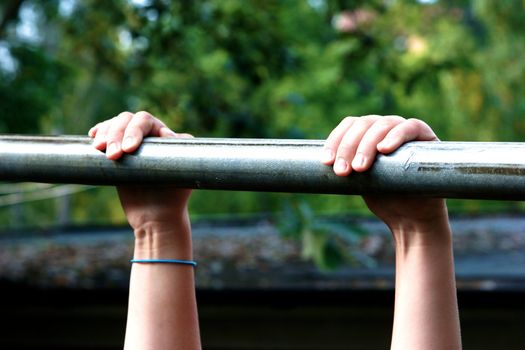 Young strong teenage athlete doing pull-up on horizontal bar