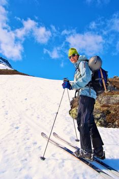 Mountaineer walking on snow mountain under blue sky.