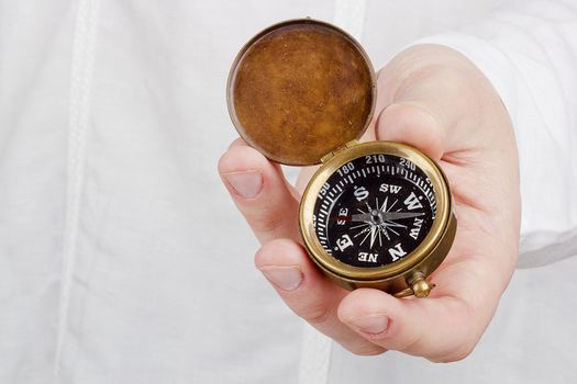 Close-up photograph of a hand holding an old compass.