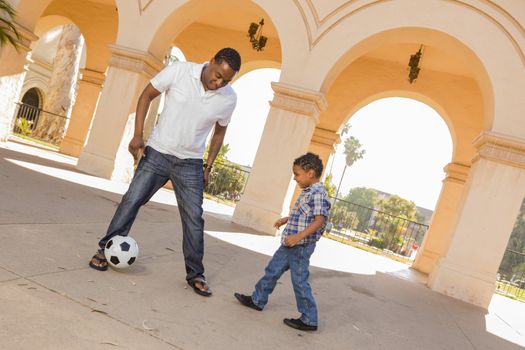 Mixed Race Father and Son Playing Soccer Outside in the Courtyard.