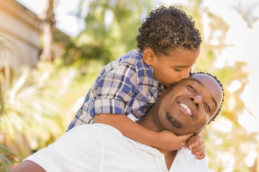 Happy African American Father and Mixed Race Son Playing Piggyback in the Park.