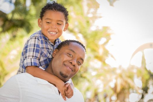 Happy African American Father and Mixed Race Son Playing Piggyback in the Park.