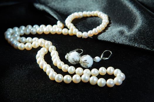  White necklace and earrings on a black fabric