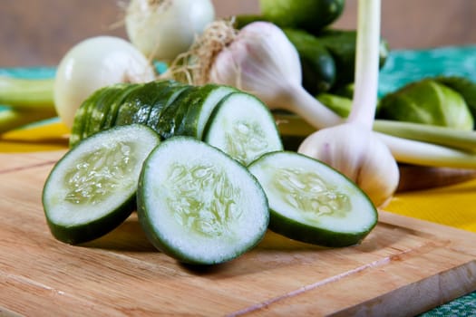 The cut green cucumber with garlic and an onions on a table