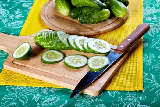 The cut green cucumbers and knife on a kitchen table