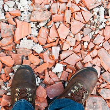 worker boots detail at a construction site (square picture with red bricks as background or texture)