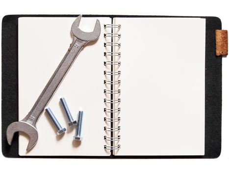 wrench and nuts on notebook, isolated on white background     