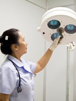 Nurse with surgical lamp in operation room