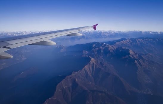 jet plane wing and Italy Alps view